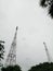 Transmission tower structure for television broadcasting built using steel frame and trusses with cloudy sky background and trees.
