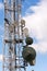 Transmitters and aerials on telecommunication tower with cloudy blue sky