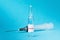 Transparent ampoule with a virus vaccine and a syringe on a blue background