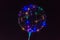 A transparent balloon glows with lamps different colors on black