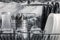 Transparent and black and white dishes as well as cutlery and glasses are washed in the dishwasher, inside view, drops and