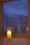 Transparent candle holder. White paraffin candle. Romantic light in the darkness. Candle on display by the window