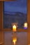 Transparent candle holder. White paraffin candle. Romantic light in the darkness. Candle on display by the window