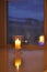 Transparent candle holder. White paraffin candle. Romantic light in the darkness. Candle on display by the window