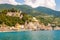 Transparent, clear water of Ligurian Sea, the beach full of people, colorful waterfront buildings and vineyard, olive terraces on