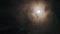 Transparent cloud moving across sky past bright full moon at night in dark.