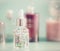 Transparent cosmetic bottle with liquid, pipette and little pink flowers. Floral essence or herbal extract serum on table, front v