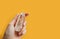 Transparent crystal of mountain quartz in a hand on a yellow background. Place for text