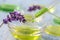 Transparent cup with drops lavender Essential liquid in dropper on wooden background with medicinal flowers