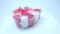 transparent gift box with a ribbon in the shape of a heart with small flowers on a white background, copying the space