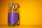 Transparent glass bottle with magenta liquid on yellow background with copy space. Closeup of perfume bottle