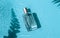 Transparent glass cosmetic perfume bottle in the blue water under shadows of tropical leaves.