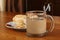 Transparent glass cup with coffee and milk and plate with cake on a table