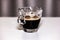 A transparent glass cup with creamy espresso, the cream of the coffee is a roasted brown and resembles the beans of the toasted co