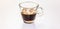 A transparent glass cup with creamy espresso, the cream of the coffee is a roasted brown and resembles the beans of the toasted co