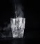 Transparent glass cup with swell the boiling water into it. The vapor from the top. Black background.