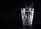 Transparent glass cup with swell the boiling water into it. The vapor from the top. Black background.