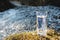 A transparent glass glass with drinking mountain water stands in the moss stone on sun beame against a background of a