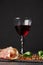 A transparent glass of red wine and a pile of cut ham on a black background. Tasty prosciutto, spicy green basil and