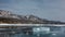 A transparent glittering ice floe lies on the frozen mirror surface of the lake