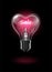 Transparent glowing heart-shaped light bulb on a dark background with the word Sale instead of a tungsten filament. Highly