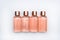 Transparent liquid soap, peach color, with air bubble in little tester bottles, top view on structured white background, mockup