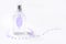 Transparent perfume bottle on a white background decorated with purple flower petals.