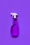 Transparent purple spray bottle with window cleaner on purple background.