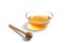 Transparent saucer with honey. A spoon for honey lies on the table. White  background