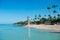 Transparent sea water and clear sky. Lighthouse on a sandy tropical island with palm trees.