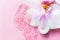 Transparent serum smear, orchid flower closeup in beautiful style on Pink background. Liquid gel cosmetic smudge