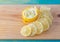 Transparent slices of lemon and peel on a cutting wooden board and blue surface. Healthy vegetarian food.