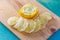 Transparent slices of lemon and peel on a cutting wooden board and blue surface. Healthy vegetarian food. Top view.