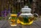 Transparent teapot and a Cup of herbal tea on a wooden table on a blurred background