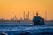 Transport boat leaving the petroleum refinery during sunset