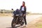 Transport and extreme concept. Thoughtful stylish female motorcyclist enjoys high speed, poses on fast bike, breathes fresh air, c