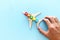 Transportation concept image, man`s hand holding toy airplane with people icons over blue background. Travel and leadership idea