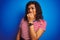 Transsexual transgender woman wearing stiped t-shirt over isolated blue background looking stressed and nervous with hands on