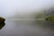Transsylvania foggy lake and rocks in Fagaras, Lake Bilea
