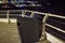 Trash bin on the pier with the sea lapping the shore and the distant lights twinkling away
