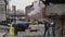 Trash blows in the wind with the backdrop of New York\\\'s east side seaport and a venting steam pipe as a taxi cab passes by