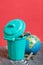 Trash can with lid filled with waste batteries. The batteries are covered with corrosion. Nearby lies a globe. Environmental Day