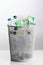 Trash can with wasted plastic bottles, grey background