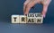 Trash to treasure symbol. Businessman turns cubes and changes the word trash to treasure. Beautiful grey table, grey background.