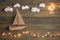 Travel and adventure creative concept - toy boat on a wooden background with cotton clouds. Christmas lights as a sea waves