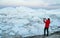 Travel in arctic landscape nature with icebergs. Greenland tourist man explorer taking photo with phone of amazing