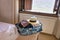 A travel bag with female clothes, straw hat, mask, hand sanitiser over a hotel room.