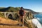 Travel in Big Sur, man Hiker with backpack enjoying view Bixby Bridge, California, USA