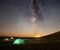 Travel and camping concept - three glowing camping tents at night under a starry sky with milky way and setting sun