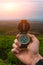 Travel, camping, orienteering and navigation concept - black magnetic compass close-up in a man s hand, blurred landscape